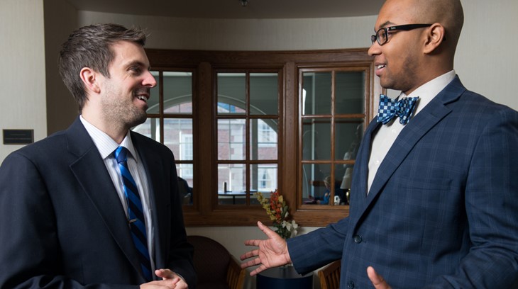 Two business students shake hands and smile