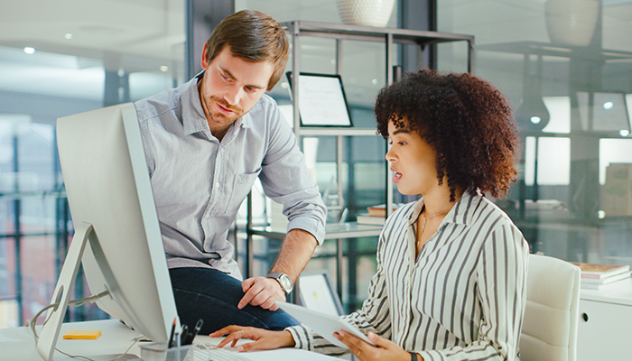 Two individuals sitting and looking at a computer