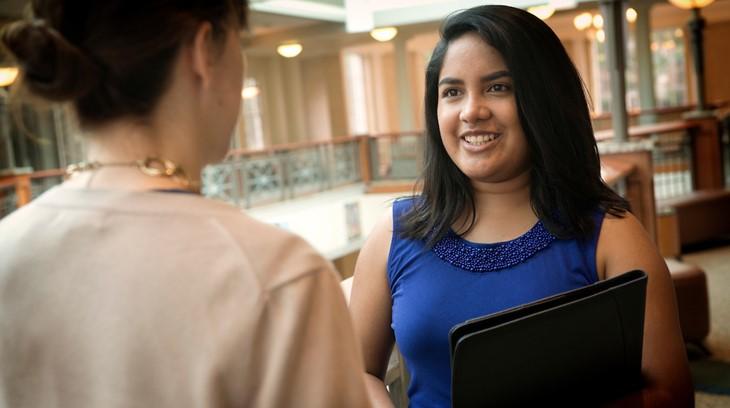 Woman smiles while talking to another woman in the foreground