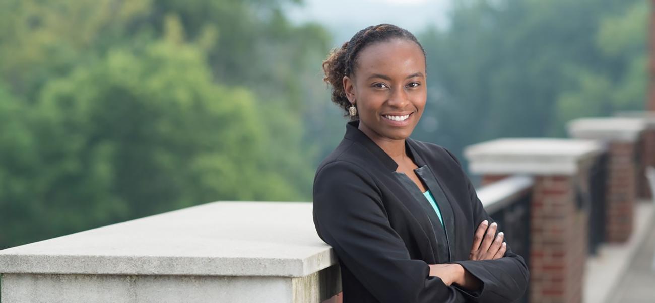 College of Business student crosses her arms and smiles outdoors