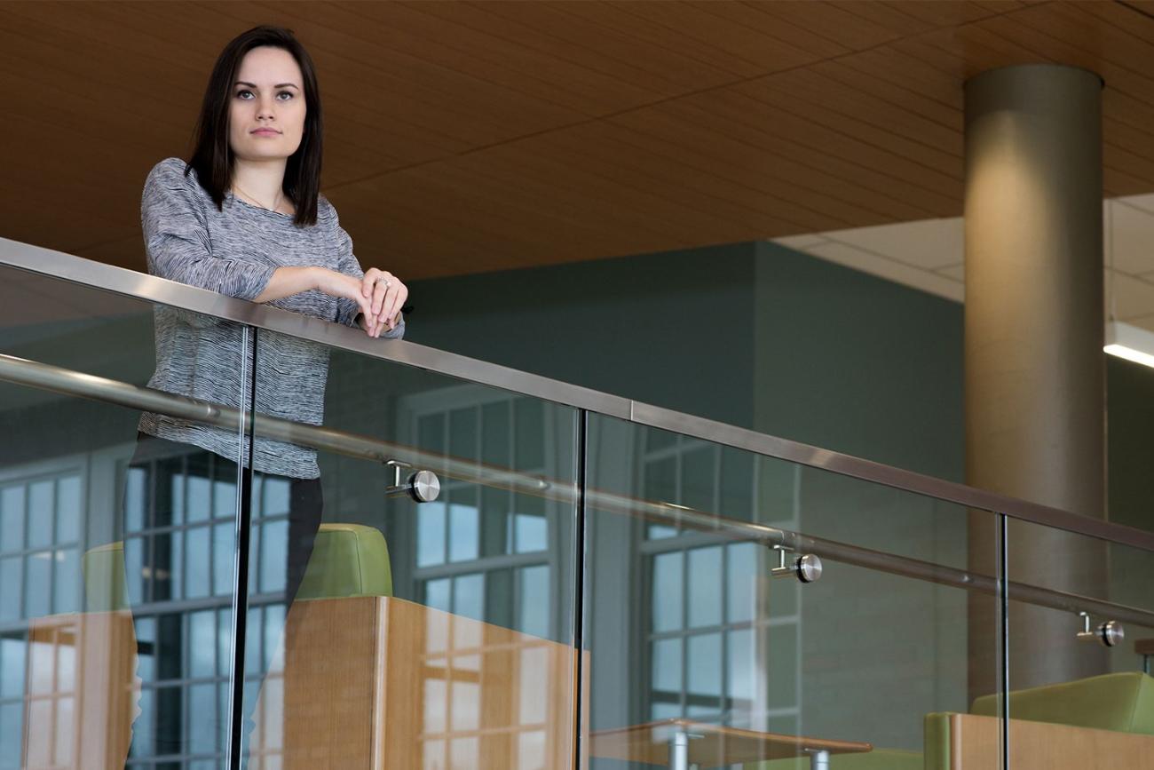 Brunette lady in gray sweater standing at glass railing