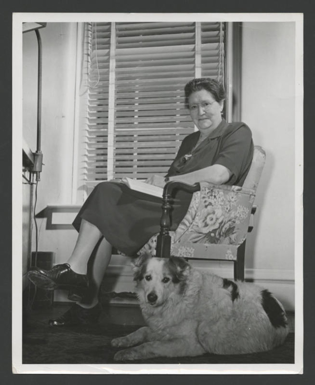 	 Irma Voigt, Ohio University dean of women, looks up from book while her dog Lady lies beside her, circa 1947