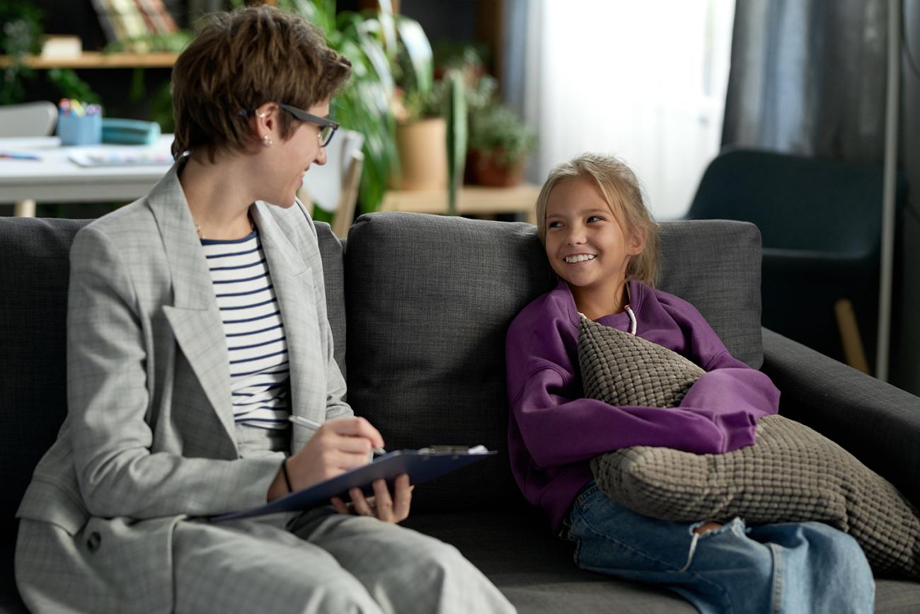 Social worker writing on a clipboard while talking to a child