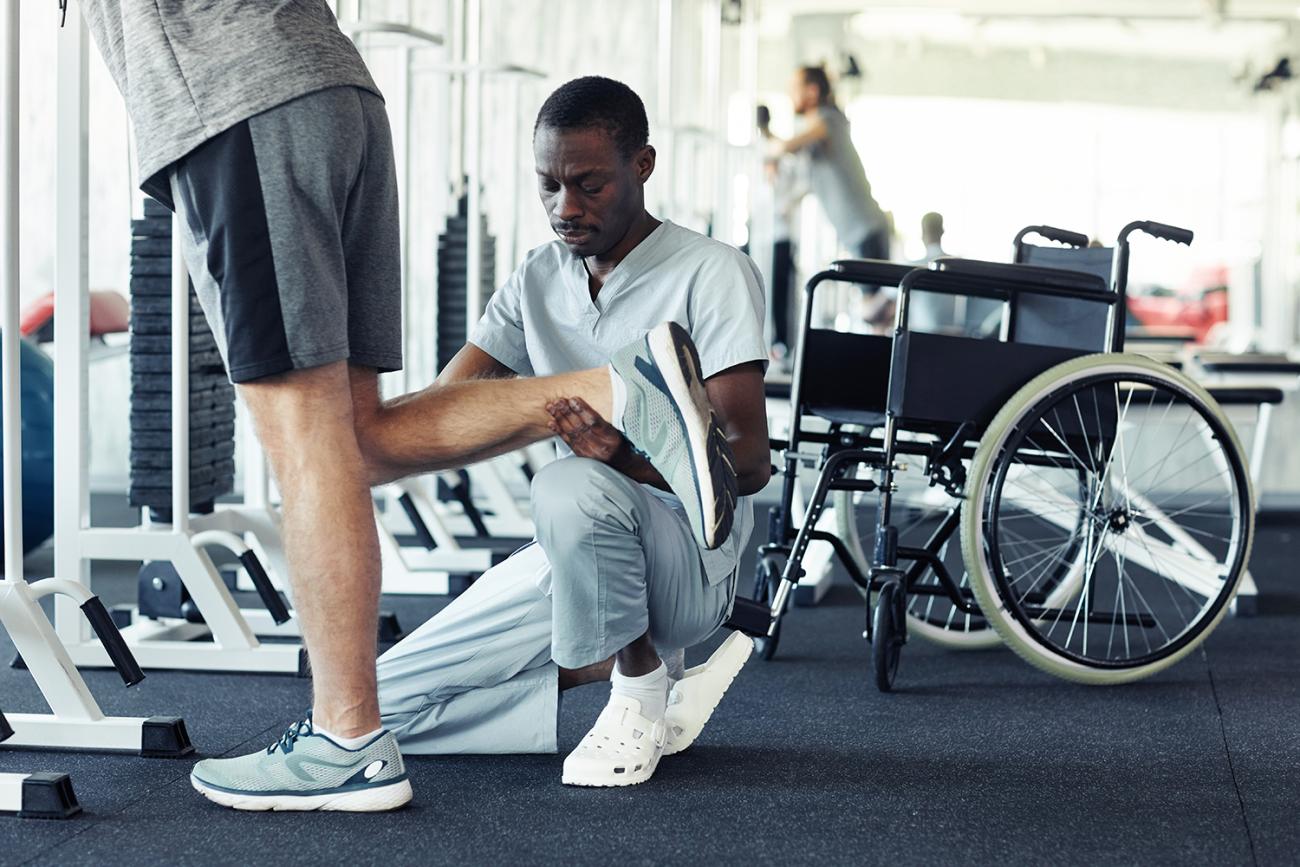 Doctor helps patient stretch his leg in a gym setting