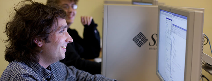 Two smiling students using Sun workstations