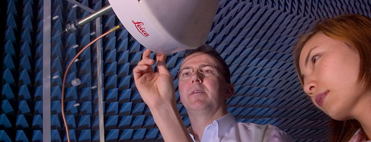 Two researchers using a Leica brand machine inside a soundproofed room