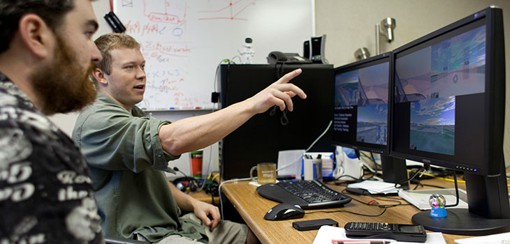 Two men looking at a computer simulation