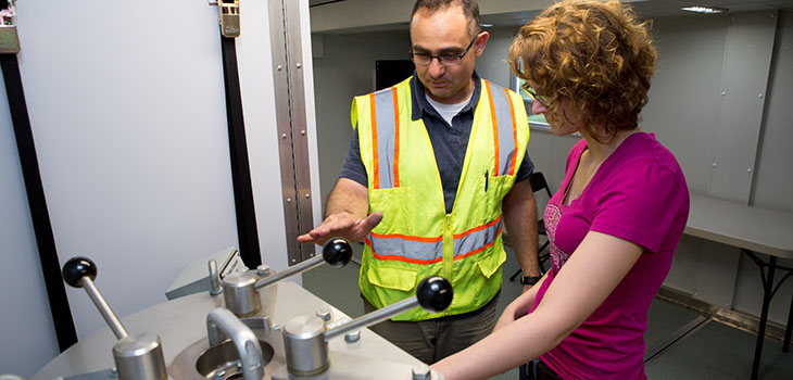 Two people looking at levers on a machine