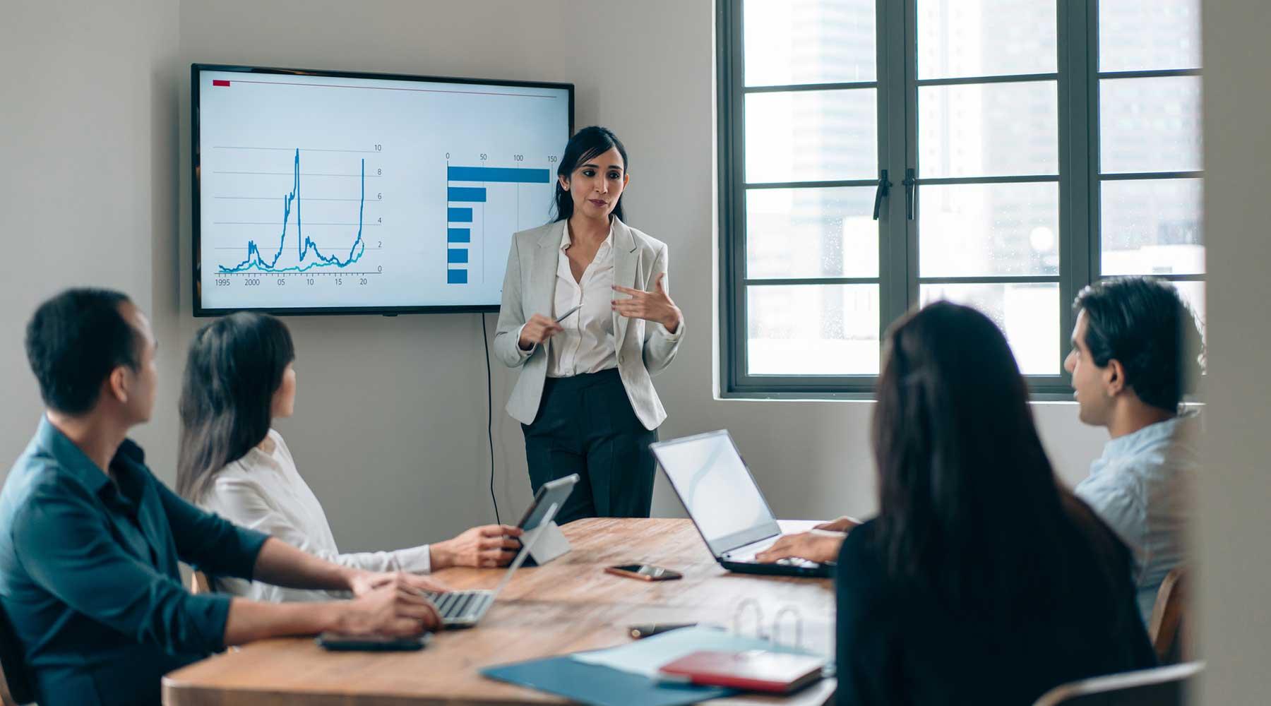 Woman standing in front of screen with graphs teaching students in the six sigma black belt certificate program