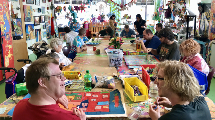 A photograph of of people sitting around a table at Passion Works, talking and working or arts and crafts