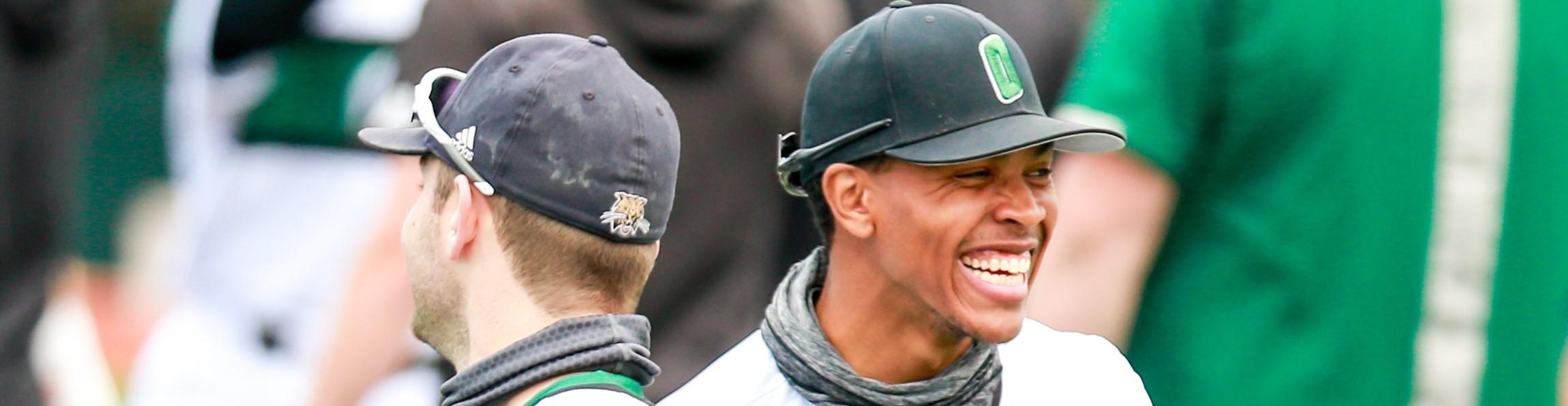 Two baseball players facing each other smiling.