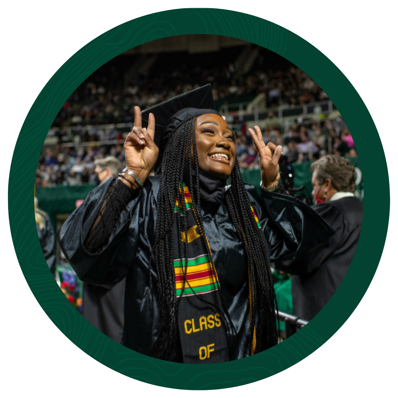 Woman in cap and gown holding her hands up in peace signs.