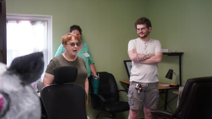 Three people standing in journalism room.