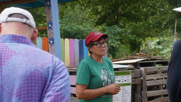 Woman in red baseball cap standing in front of compost area.
