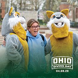 A student poses with two retro squirrel mascots.