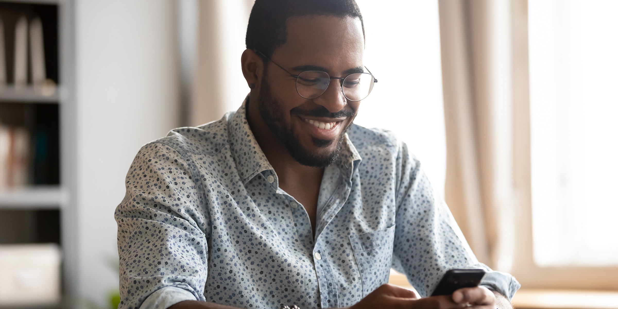Man smiles and looks at smart phone
